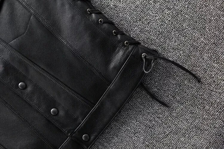 Close-up of a black leather jacket with buttons on a textured gray surface
