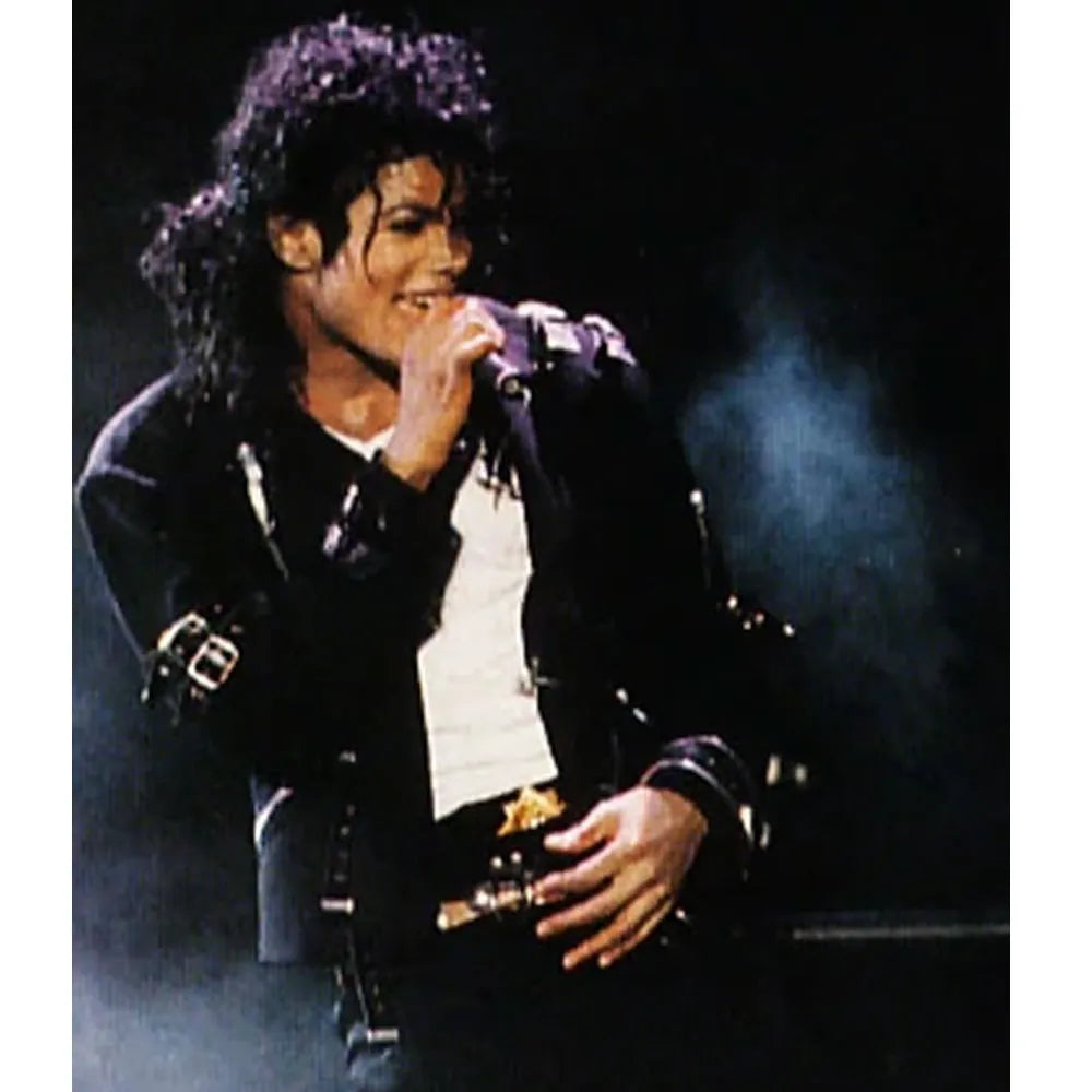 Person in a black leather jacket with a microphone, performing on stage.