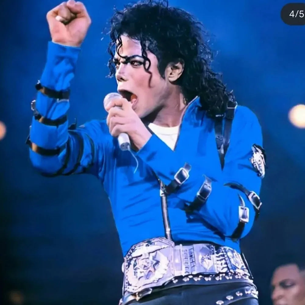 Person in a blue outfit with decorative elements, holding a microphone on a stage.