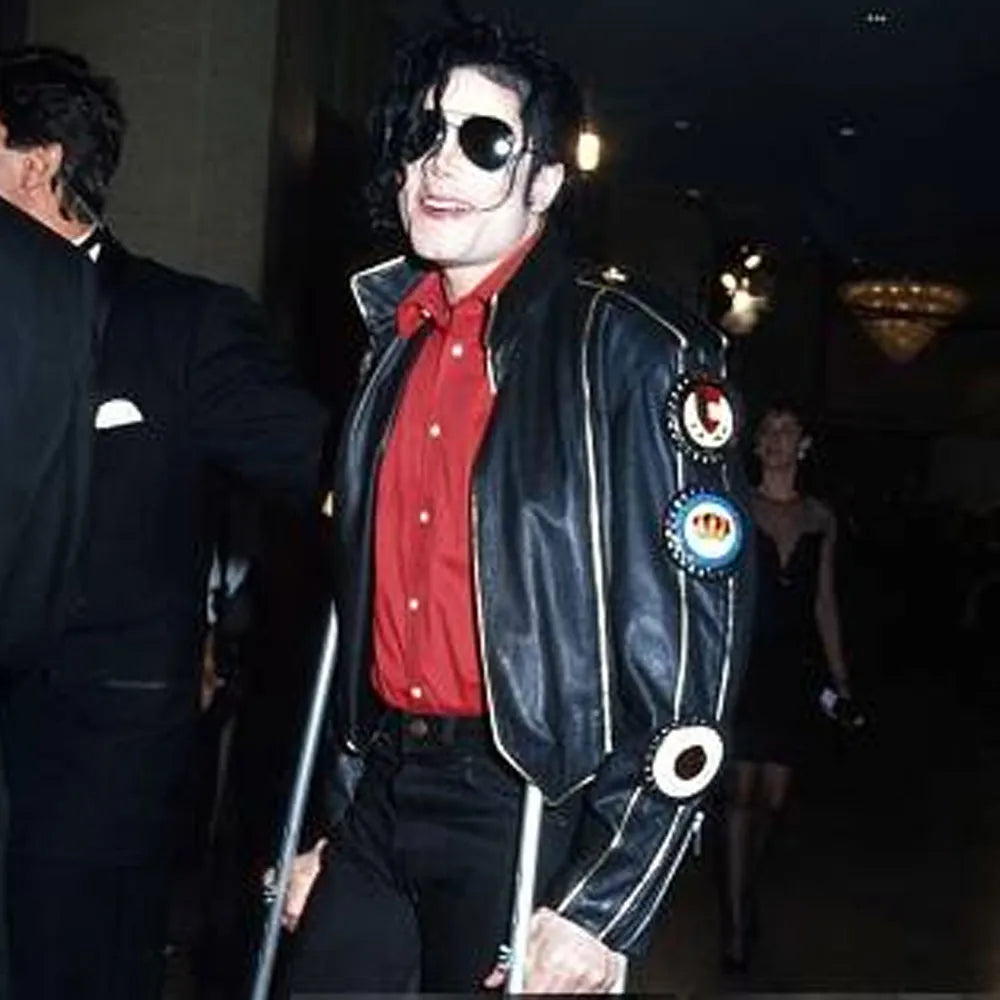 Person wearing a black leather jacket with decorative buttons, holding crutches.