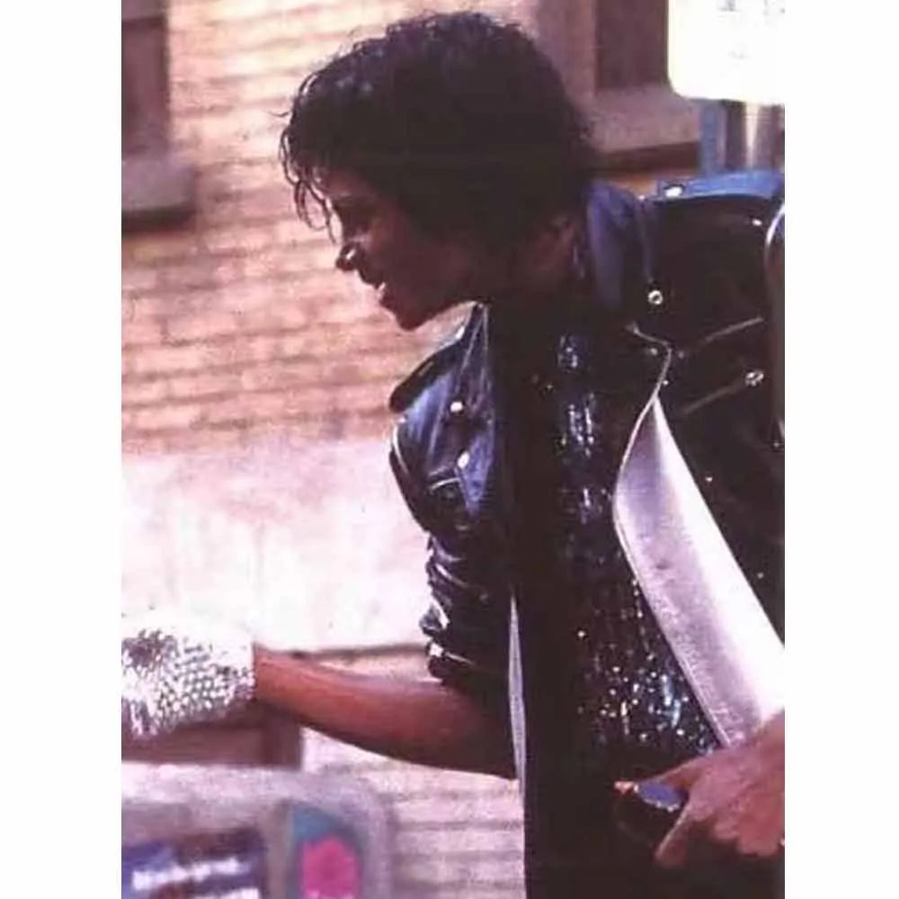 Person wearing a black leather jacket with reflective elements, standing against a blurred background.
