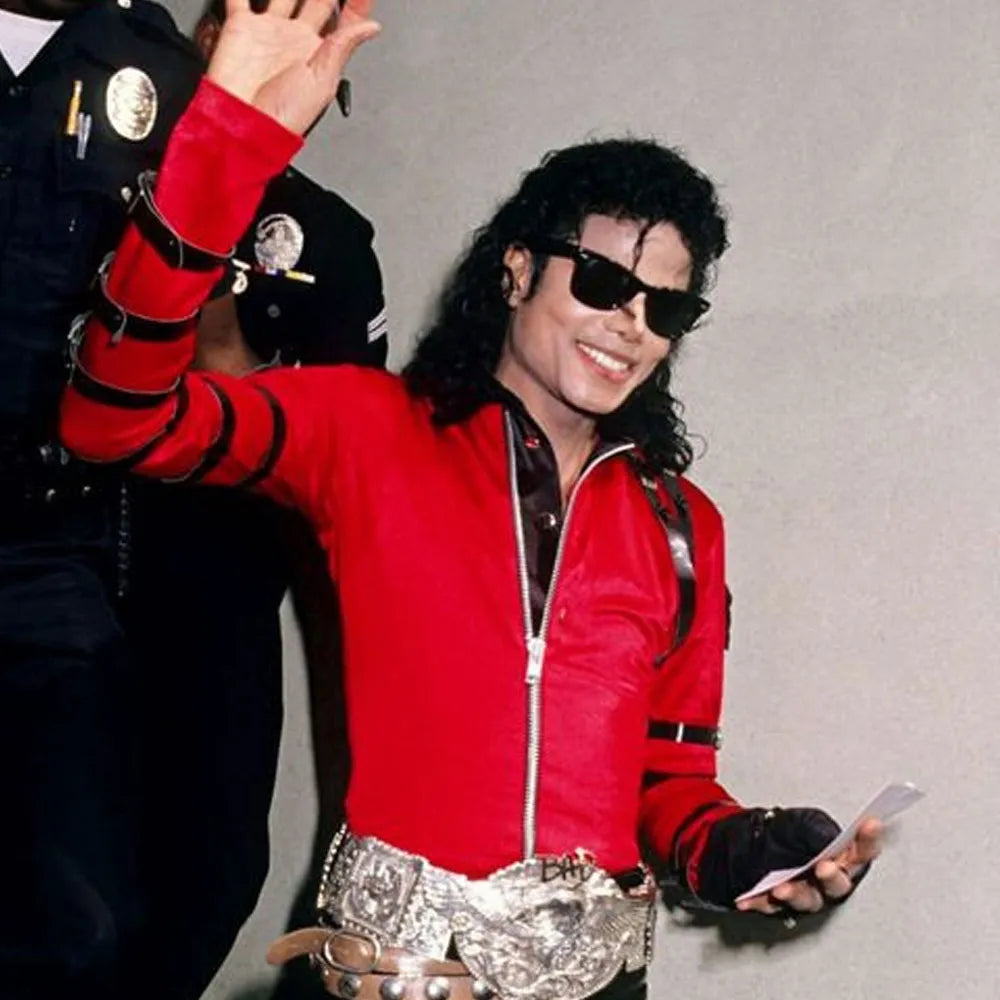 Person wearing a red jacket with black accents, holding a phone, with a plain background