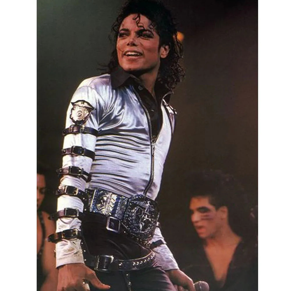 Person wearing a white jacket with black accents and a belt, standing on a stage.